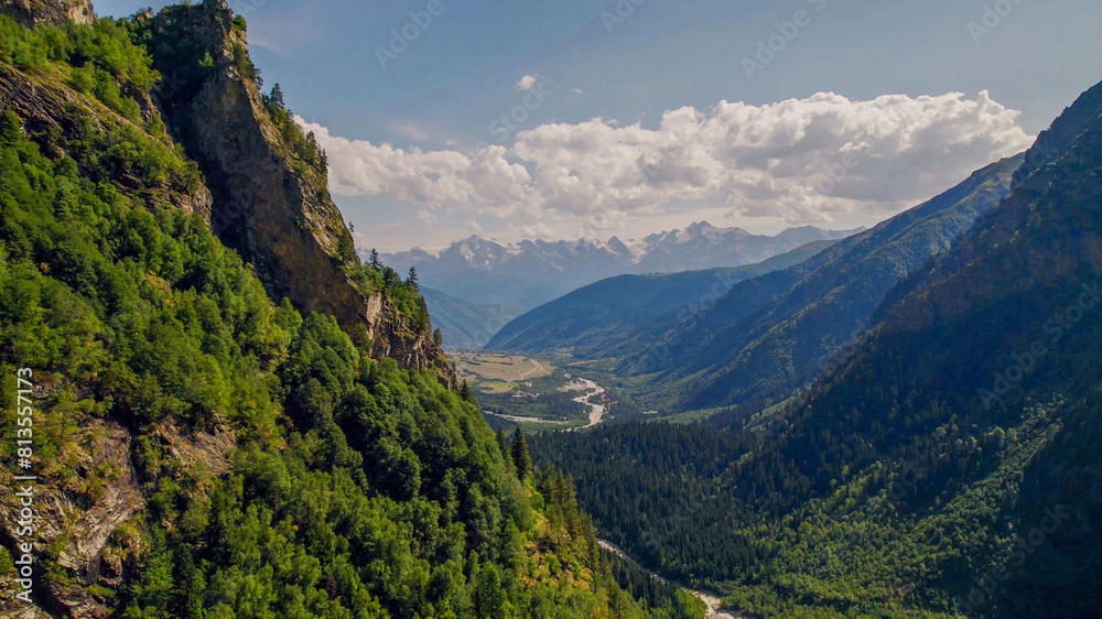 Breathtaking view of a verdant alpine valley and towering mountains under a clear sky, ideal for Earth Day and environmental conservation themes