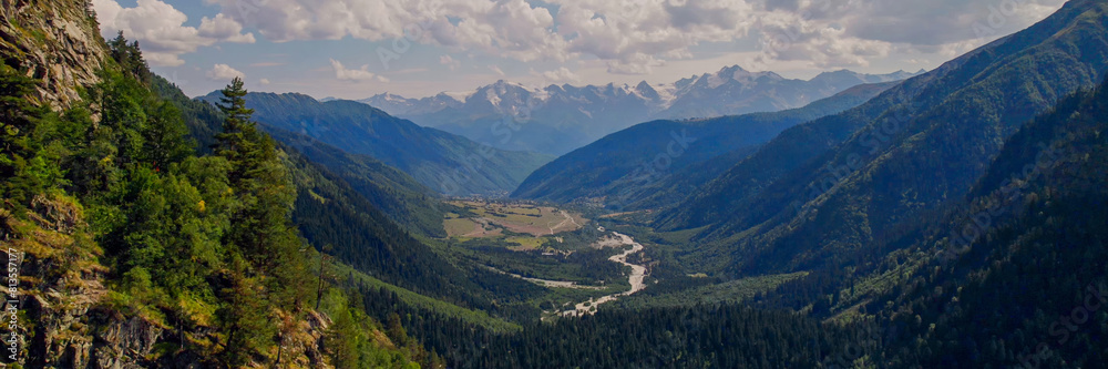 Breathtaking view of a verdant alpine valley and towering mountains under a clear sky, ideal for Earth Day and environmental conservation themes