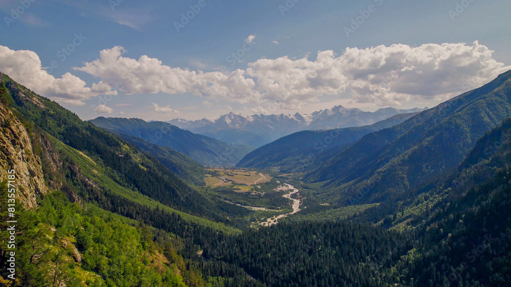 Breathtaking view of a verdant alpine valley and towering mountains under a clear sky, ideal for Earth Day and environmental conservation themes Breathtaking view of a verdant alpine valley and towering mountains under a clear sky, ideal for Earth Day and environmental conservation themes