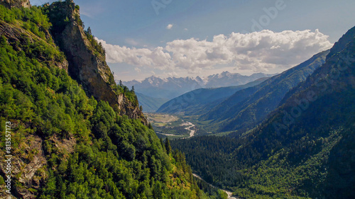 Breathtaking view of a verdant alpine valley and towering mountains under a clear sky, ideal for Earth Day and environmental conservation themes