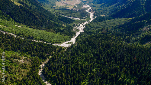 Aerial view of a meandering river cutting through a dense, green mountain valley, ideal for Earth Day themes and environmental conservation concepts
