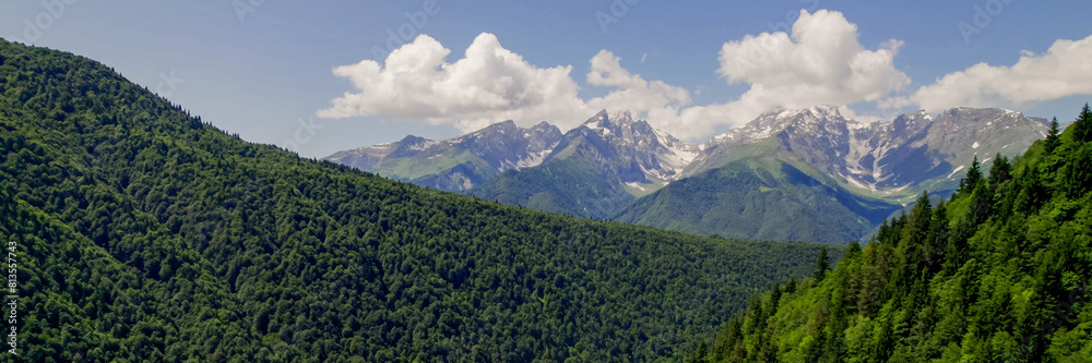 Lush green mountain slopes lead to snow-capped peaks under a clear sky, ideal for Earth Day and International Mountain Day themes