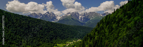 Lush green mountain slopes lead to snow-capped peaks under a clear sky, ideal for Earth Day and International Mountain Day themes