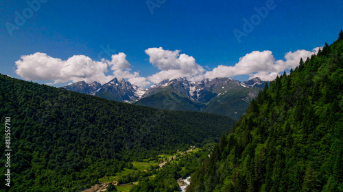 Lush green mountain slopes lead to snow-capped peaks under a clear sky, ideal for Earth Day and International Mountain Day themes