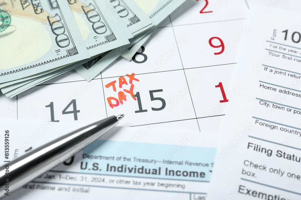 Tax day. Calendar with date reminder, documents, dollar banknotes and pen on table Tax day. Calendar with date reminder, documents, dollar banknotes and pen on table