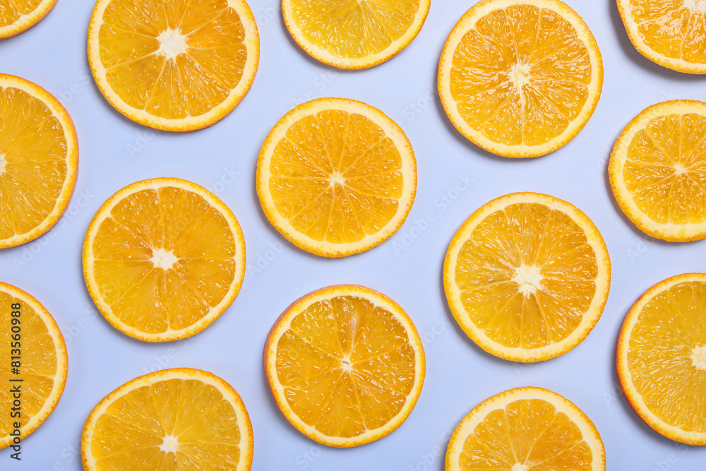 Fototapeta premium Slices of juicy orange on light blue background, flat lay