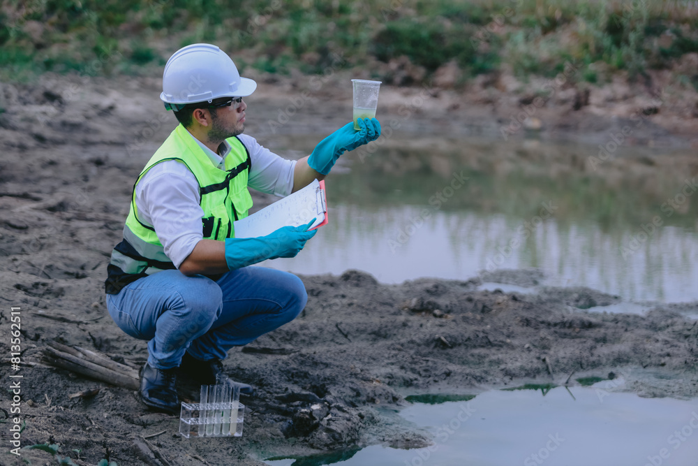 Asian man ecologist holds magnifying glass to inspect water in transparent glass at the lake. Concept, explore, analysis water quality and creature from natural source. Ecology field research. Asian man ecologist holds magnifying glass to inspect water in transparent glass at the lake. Concept, explore, analysis water quality and creature from natural source. Ecology field research.