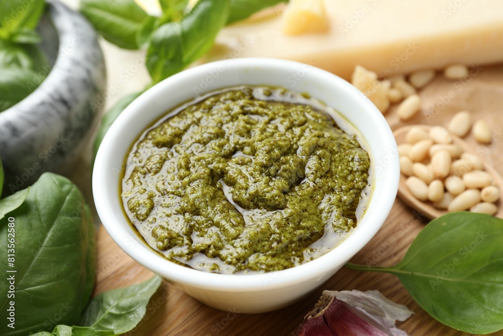 Tasty pesto sauce in bowl, basil, pine nuts and cheese on table, closeup Tasty pesto sauce in bowl, basil, pine nuts and cheese on table, closeup