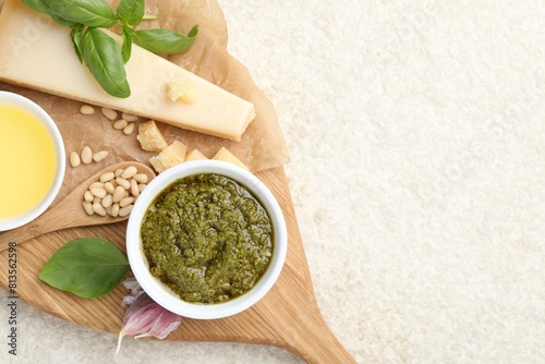 Tasty pesto sauce, basil, pine nuts, garlic, oil and cheese on light grey table, top view. Space for text