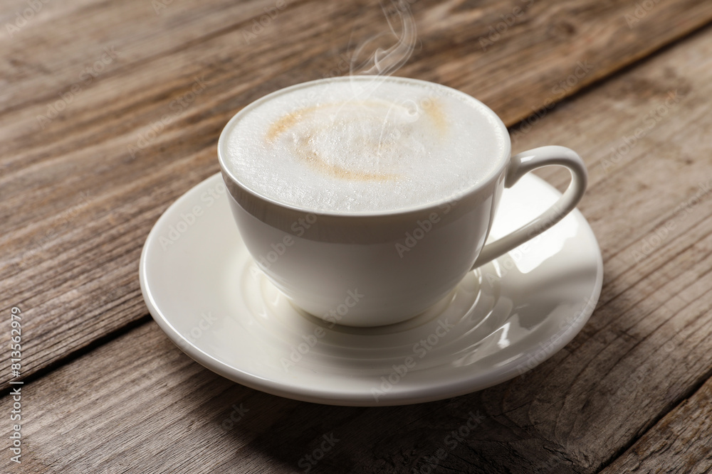 Steaming coffee in cup on wooden table Steaming coffee in cup on wooden table