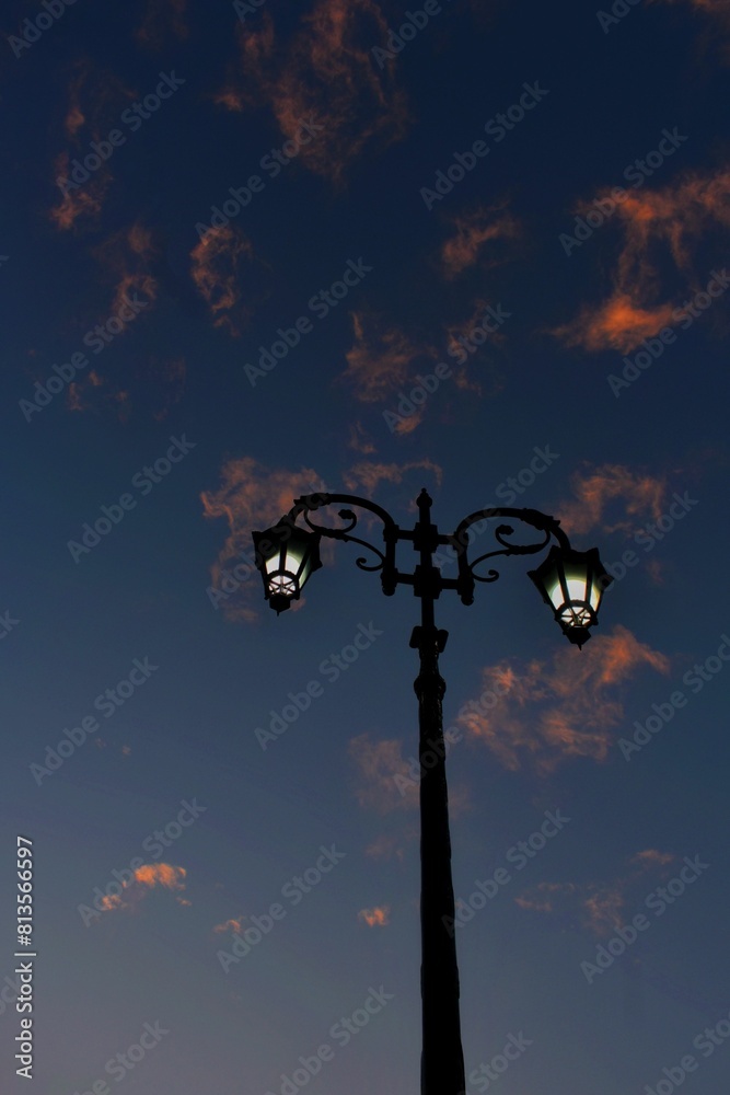 Vertical shot of a black street lamp against a cloudy sunset sky Vertical shot of a black street lamp against a cloudy sunset sky