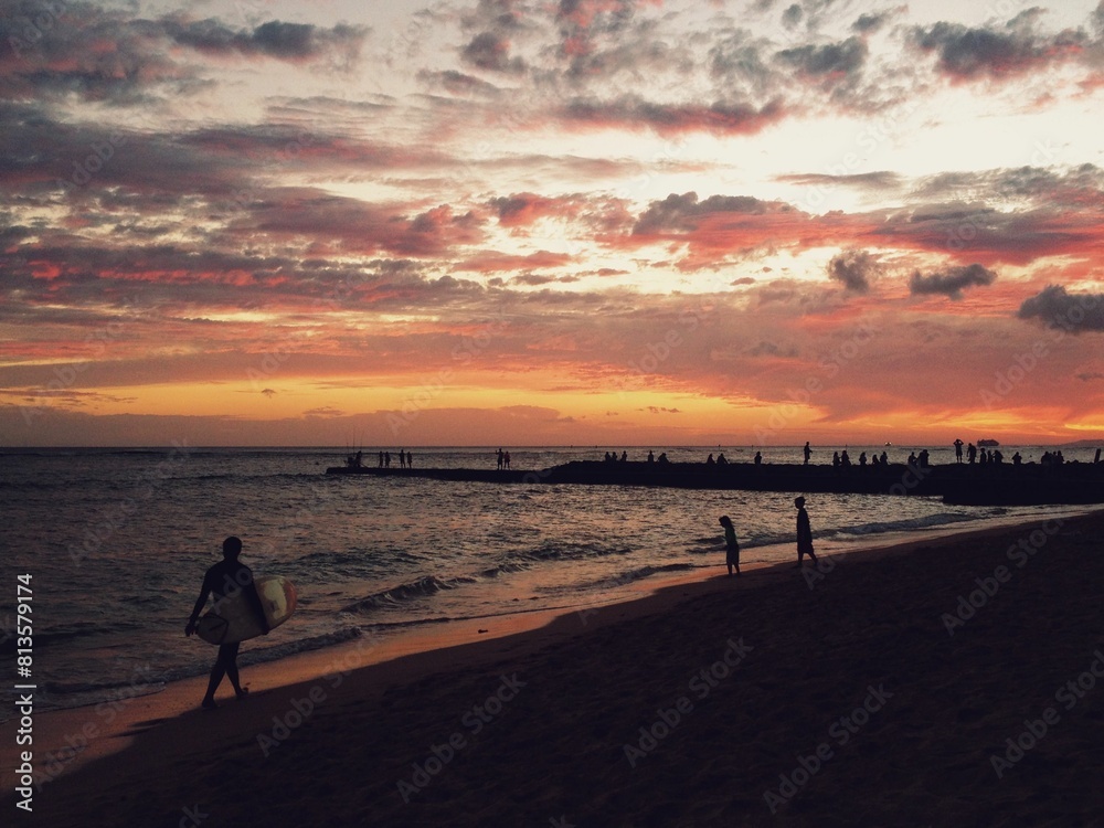 Waves washing beach with full of people against a scenic view of the sunset Waves washing beach with full of people against a scenic view of the sunset