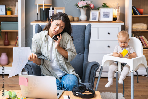 Multitasking mother. Young freelance business mom taking care of her child, young baby, and working from home on laptop computer. Woman after labor work online from apartment, with kid near her.