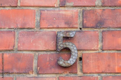house number five at an old brick wall