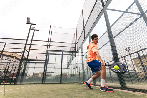 young man playing paddle tennis. low angle