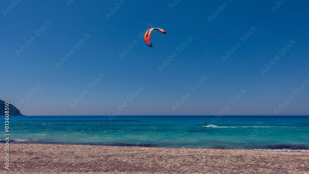 Kiteboarder pulled by a power kite across the sea against a blue sky background Kiteboarder pulled by a power kite across the sea against a blue sky background
