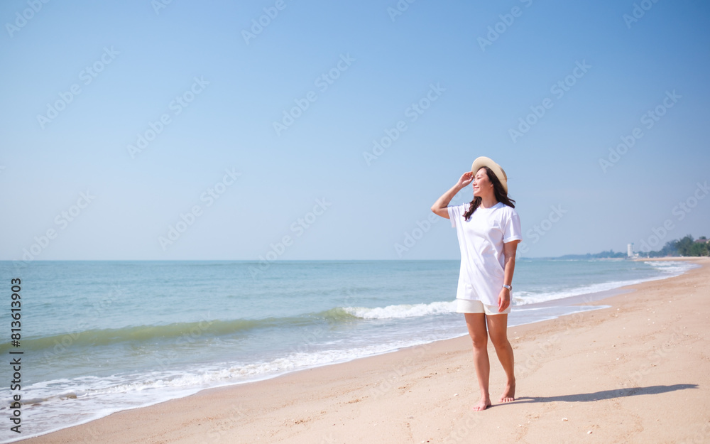 Portrait image of a young woman while strolling on the beach with the sea and blue sky background Portrait image of a young woman while strolling on the beach with the sea and blue sky background