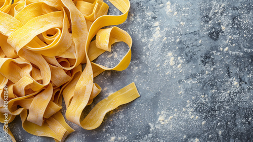 Raw yellow italian pasta pappardelle  fettuccine or tagliatelle on a blue background  close up. Egg homemade noodles cooking process  long rolled macaroni  uncooked spaghetti .