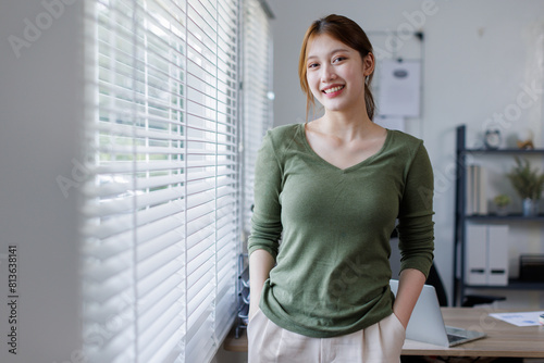 Free Download  Young Asian business woman smiling confidently while standing alone in a bright modern office - GFXLoad