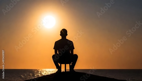 A man is seated on top of a rock with the sun radiating behind him