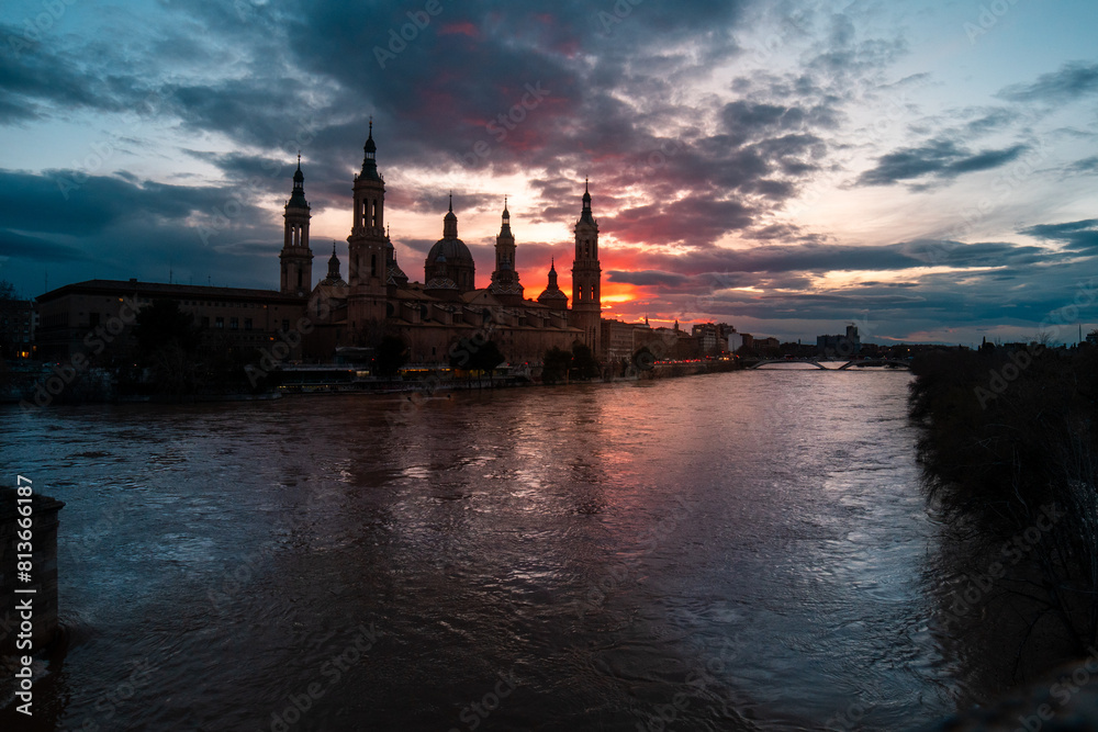 Fototapeta premium Golden Hour Glow: Capturing the Radiant Beauty of Zaragoza as the City Basks in the Warm Glow of an Orange Sunset, Painting the Skyline with a Palette of Vibrant Hues. 