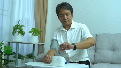 Asian man using blood pressure monitors at home health care concept. photo