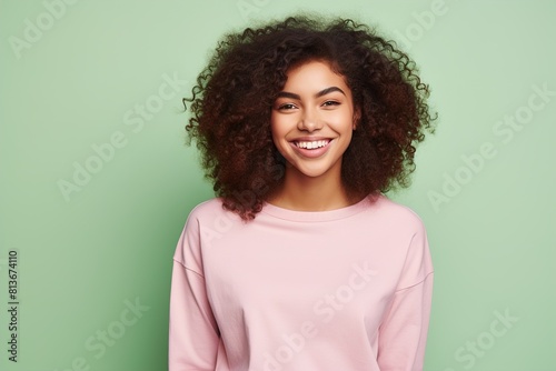 A woman with curly hair is smiling and wearing a pink shirt