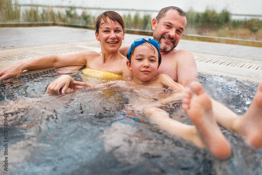 Cute boy and his parents are swimming in an open-air poo Cute boy and his parents are swimming in an open-air poo