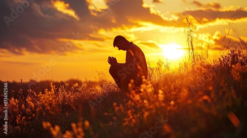 Christian prayer. Man on his knees praying on sunset background. Kneeling prayer to God. photo