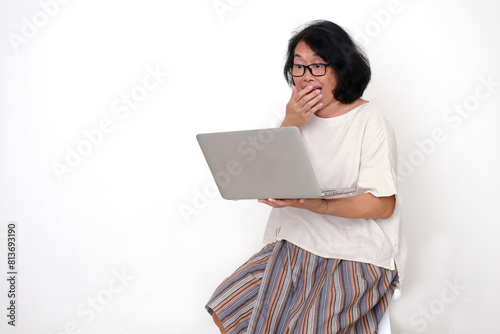 A woman is using a laptop to get connected with others; smiling, surprised, happy expression photo