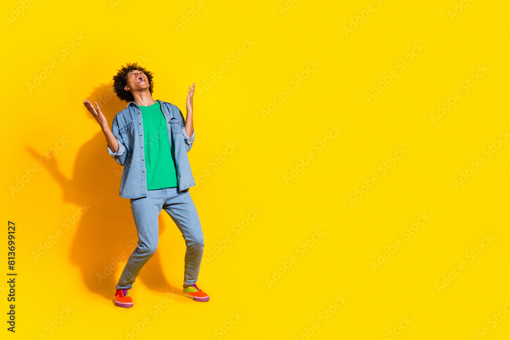 Full size portrait of nice young man scream empty space wear denim shirt isolated on yellow color background