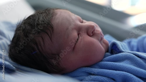 Infant newborn baby close-up face initial days right after birth, first day of a human being in the world observing his surroundings photo