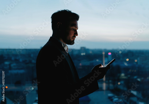 Businessman use smart phone at night in office. A man with a phone in his hands