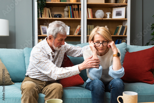 Marital problems and issues. Senior couple sitting at home and argue. Man offend woman. Husband and wife trying to find solution for their relationship and marriage. Quarrel and crisis.