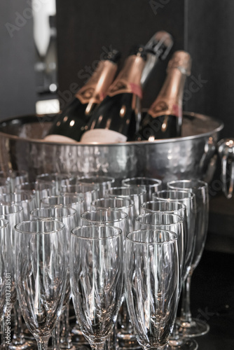 Many empty champagne glasses prepared for a gala event against on the blurred bottles background