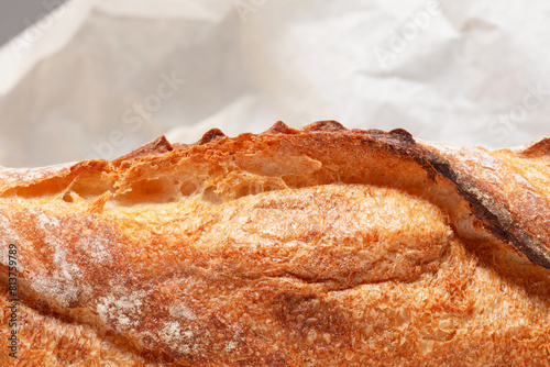 Detail of baguette bread.  Freshly baked loaf of bread on crumpled parchment paper . Shallow depth of field photo