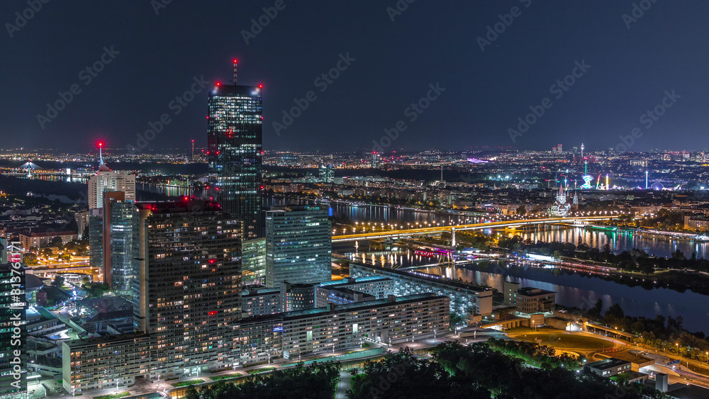 Fototapeta premium Aerial panoramic view over Vienna city with skyscrapers, historic buildings and a riverside promenade night timelapse in Austria.