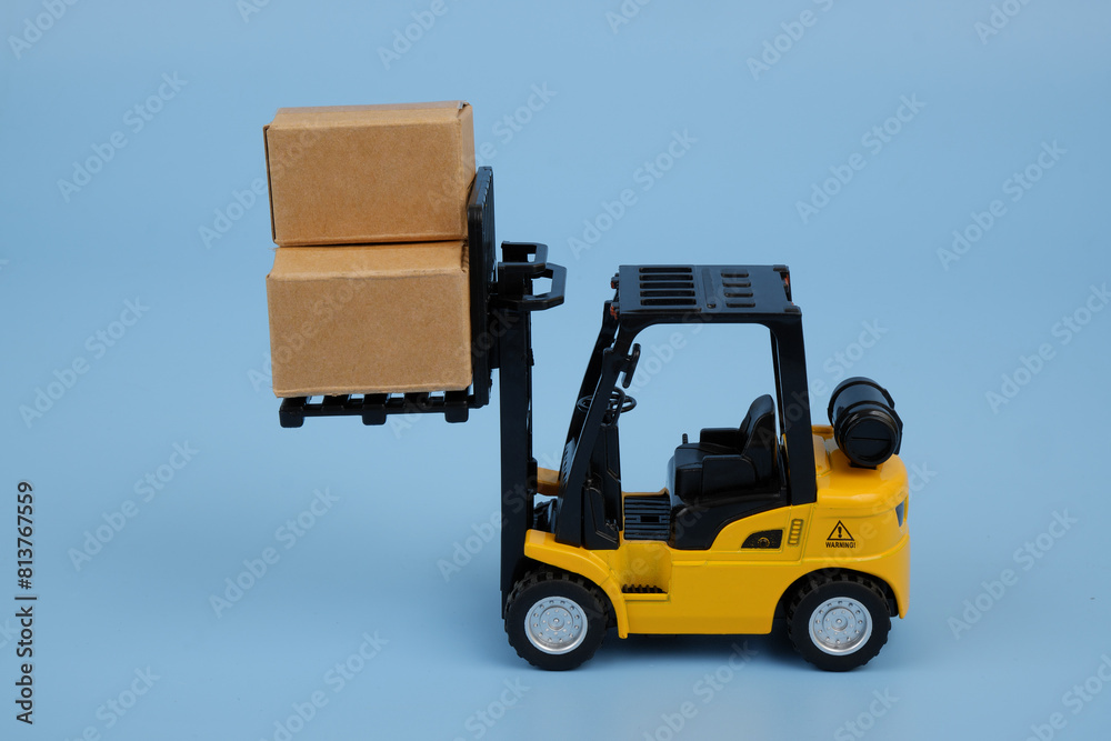 Yellow forklift truck carrying carton boxes on blue