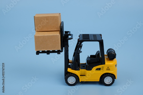 Yellow forklift truck carrying carton boxes on blue