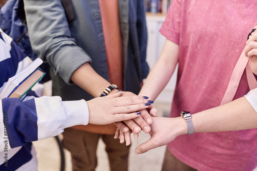 Close up of multiethnic group of students stacking hands and huddling in team spirit