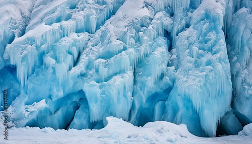 A closeup of an azure wall with peeling paint resembling a glacial landform covered in snow, creating a freezing and electric blue backdrop