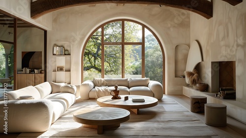 A spacious living room with an arched window featuring a cream sofa and two round coffee tables 