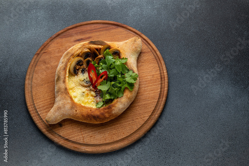 Traditional georgian khachapuri with mushrooms and cheese on a wooden board
