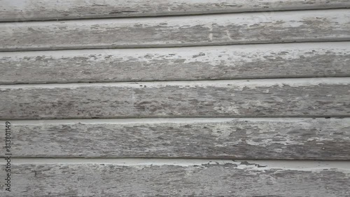Panning view of the old wooden building boards chipped and peeling painted white from old paint.