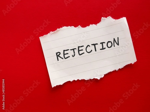 Toen paper note on red background with text written REJECTION, concept of being dismissed or refused of a proposal, idea, work, relationship or affection - refusal to accept an offer