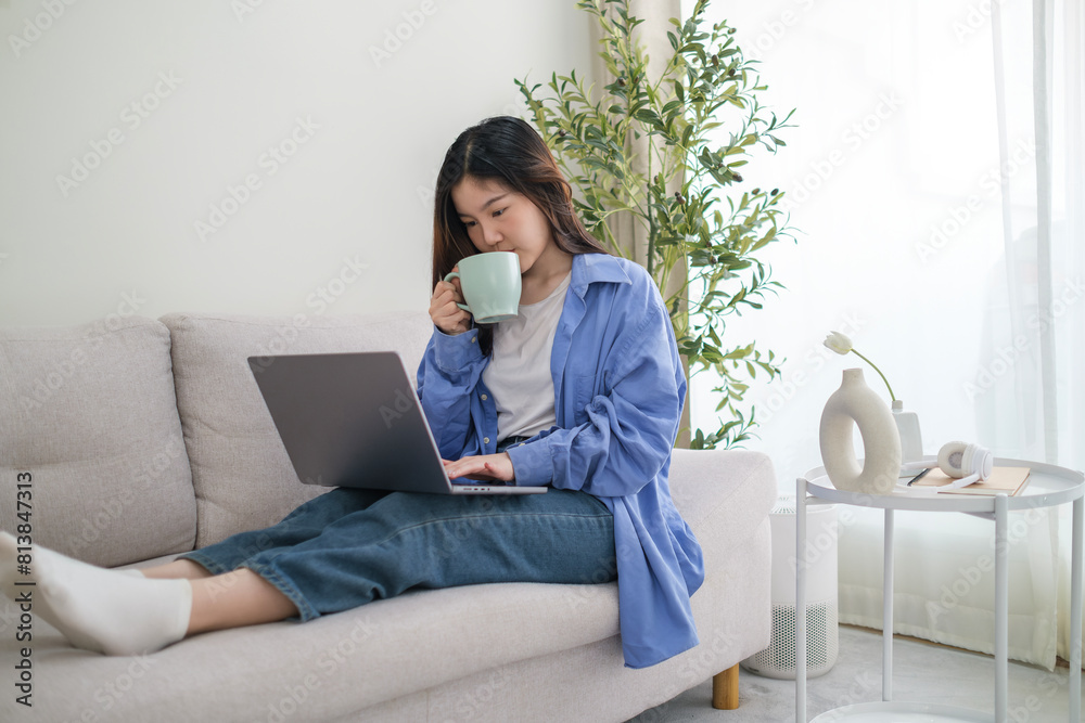 Relaxed young woman drinking coffee and using laptop on comfortable couch at home. Relaxed young woman drinking coffee and using laptop on comfortable couch at home.