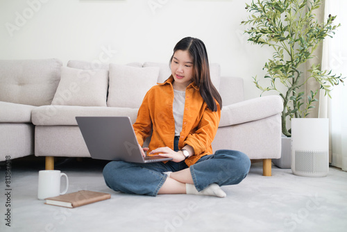 Beautiful young woman working with laptop while sitting on carpet in living room. Free Download Beautiful young woman working with laptop while sitting on carpet in living room. - GFXLoad