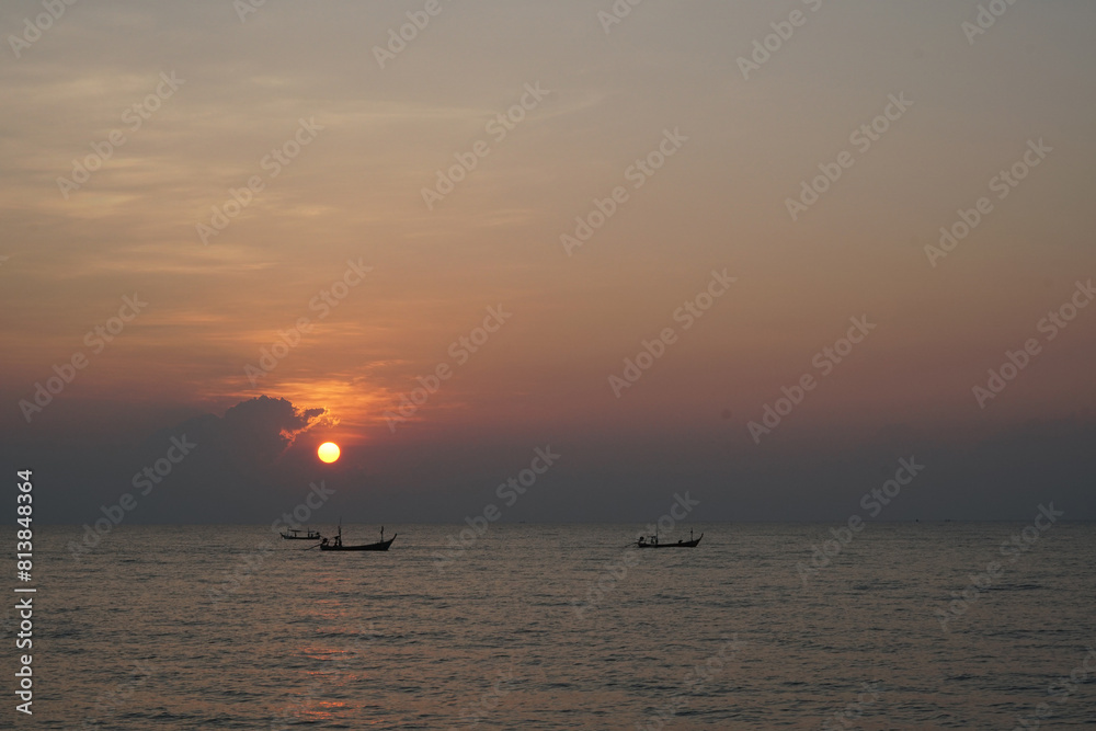 Fototapeta premium The perspective of the fishing boat in the sea with a sunrise background