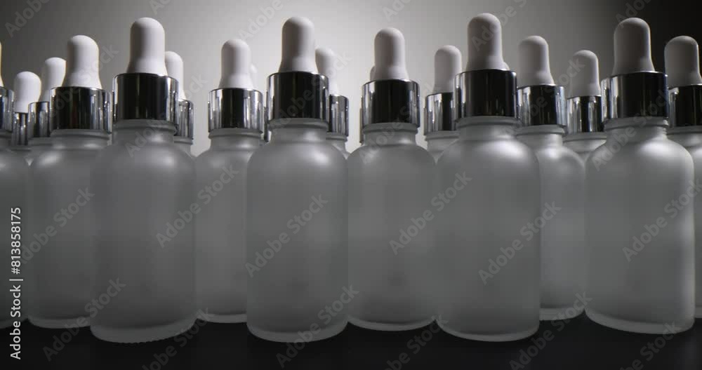 Cosmetic glass bottle with a rubber pipette on black background. Production of cosmetic bottles