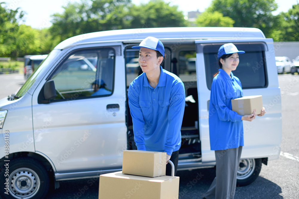 屋外で荷物を運ぶ配送ドライバーの男女 屋外で荷物を運ぶ配送ドライバーの男女